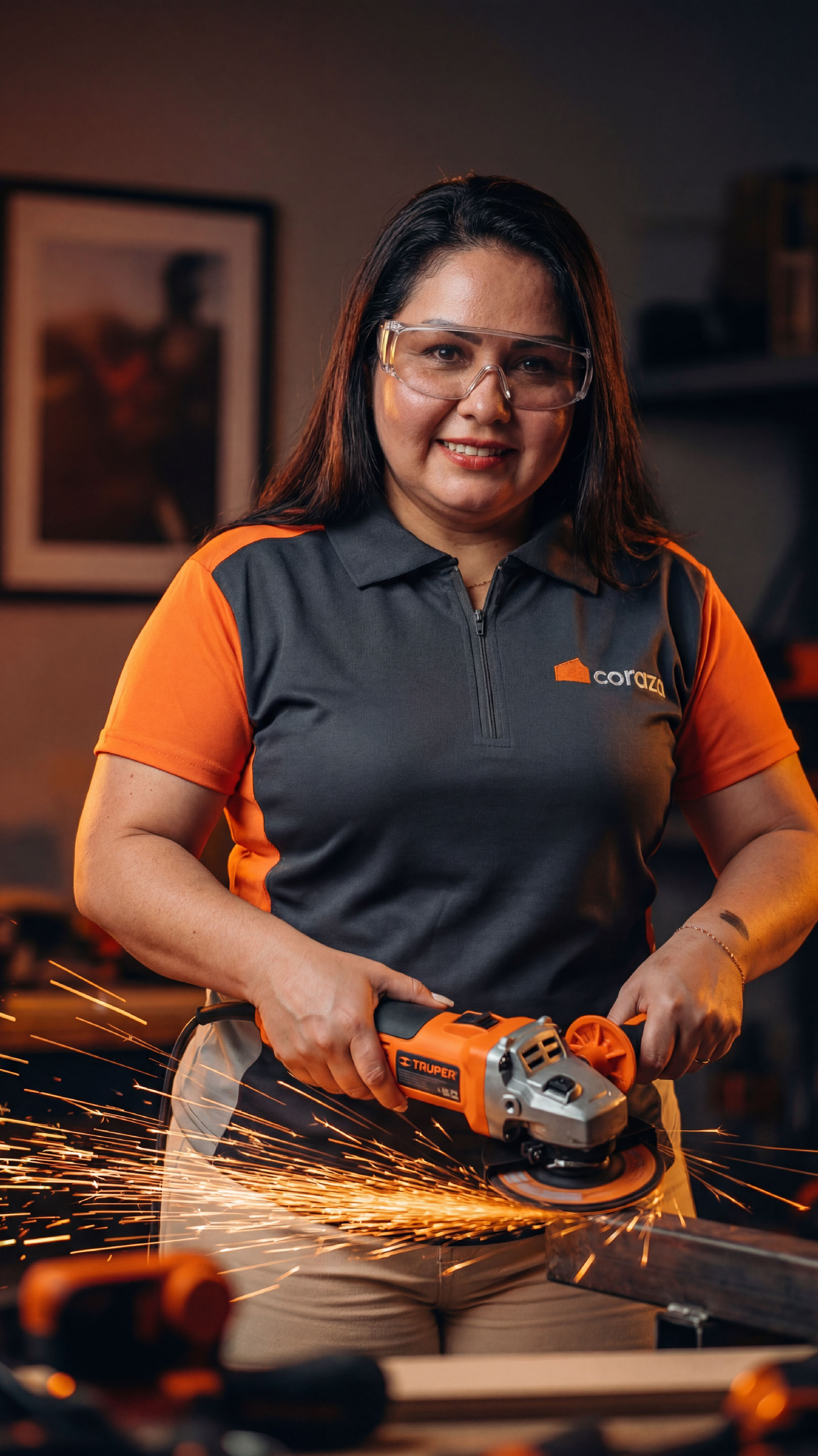 Mujer usando amoladora con chispas, uniforme Coraza